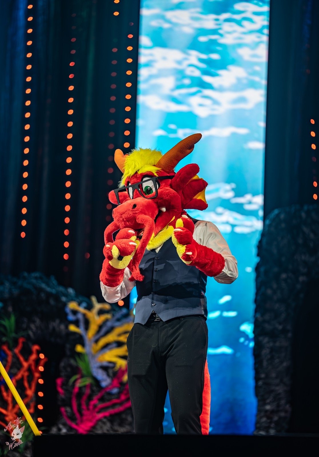 Ronnie Noodles in a waistcoat performing on stage in front of an underwater backdrop
