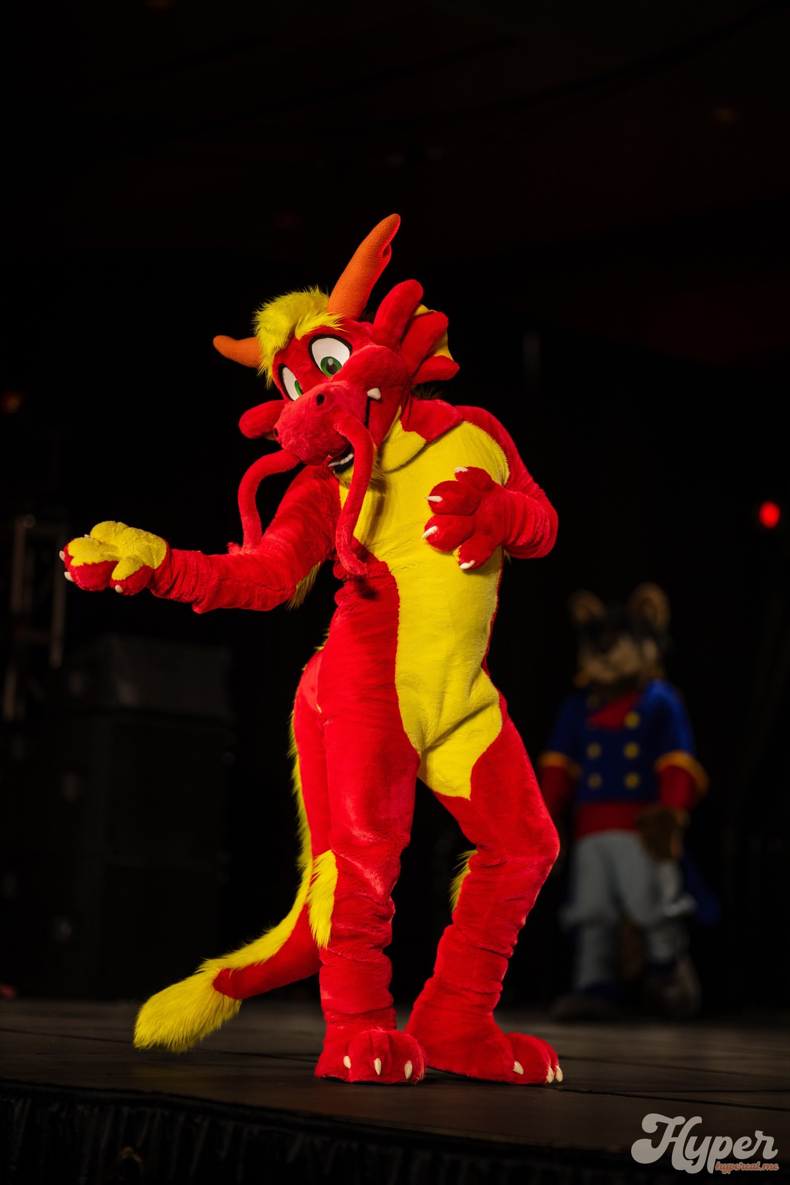 Ronnie Noodles striking a dance pose on a dark convention stage
