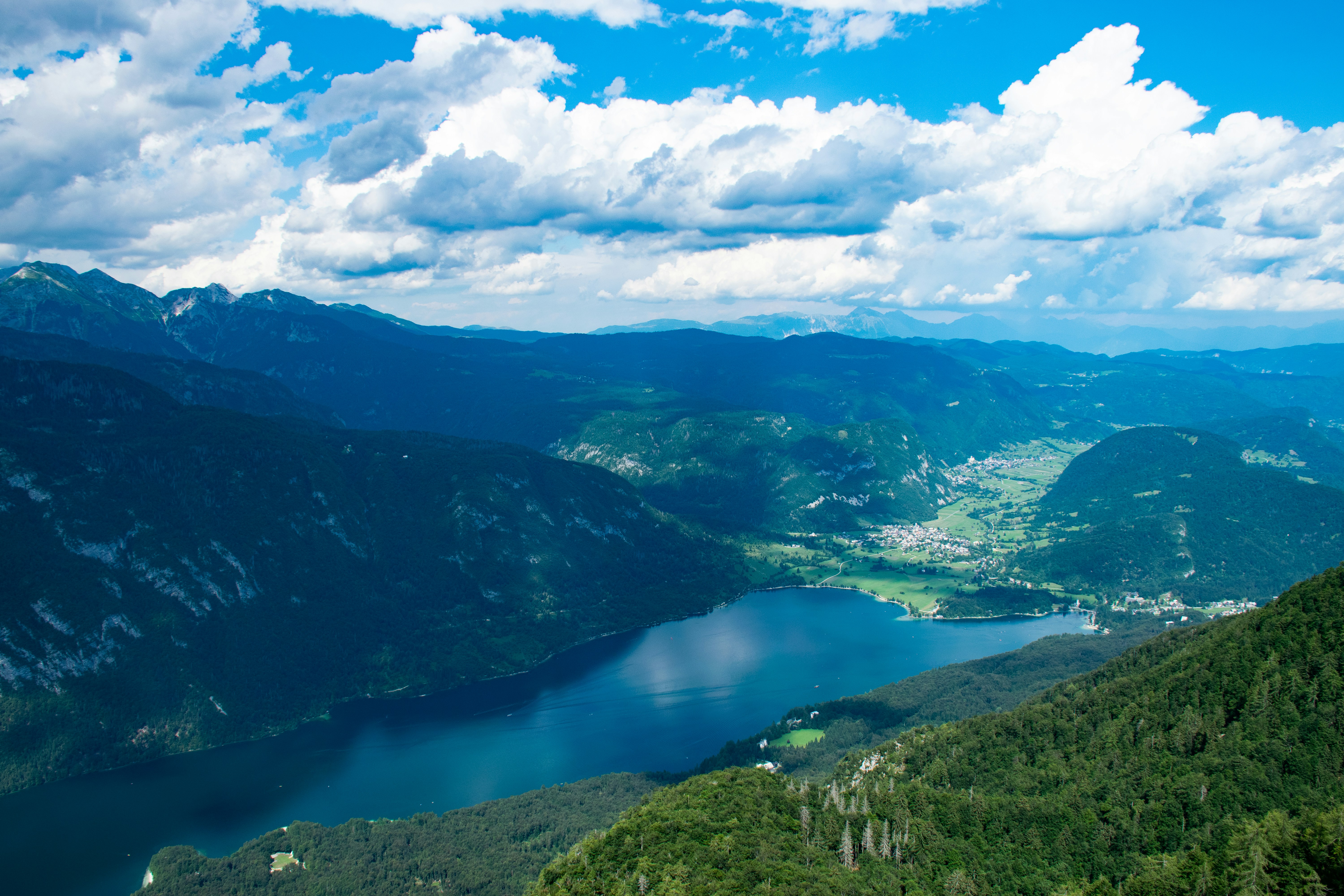 Green mountains around Lake Bohinj under white clouds and blue sky